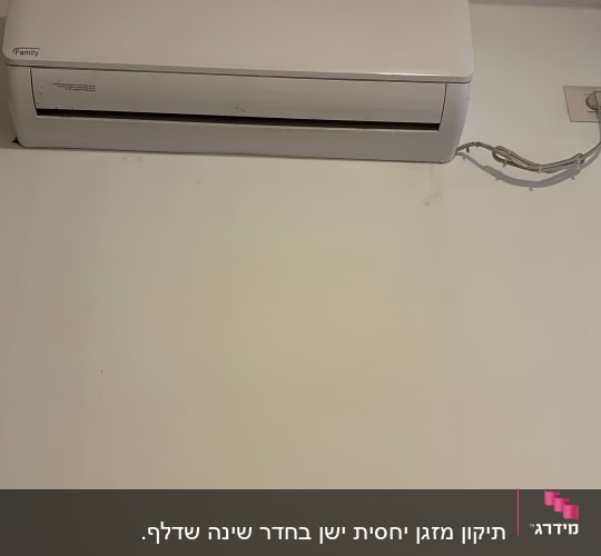 מזגן קיר לבן מותקן על קיר עם כבל חשמל